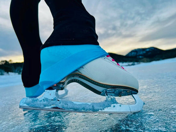 A skater's boot and blade on a frozen lake at sunset