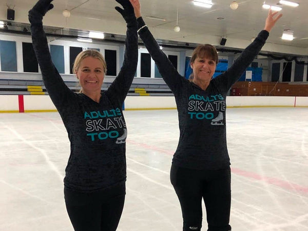 Two adult skaters in Adults Skate Too tops with their arms up on the ice