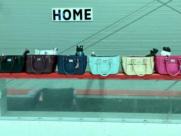 Six Rink Side Totes in different colors lined up on the rink boards under a HOME sign