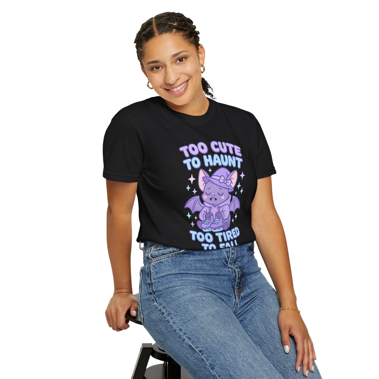 Person wearing a black t-shirt with a purple graphic and text, sitting on a stool against a white background.