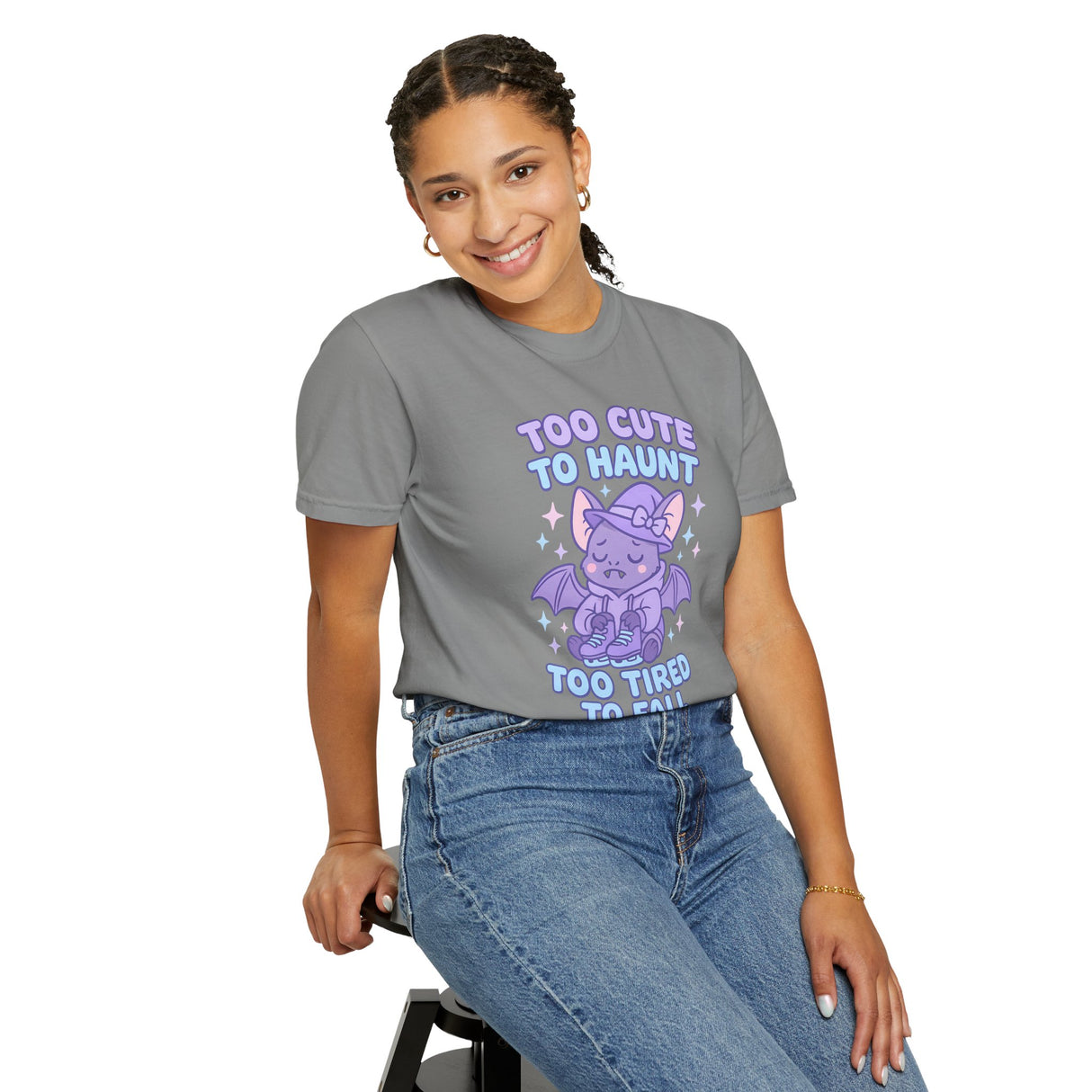 Person wearing a gray t-shirt with a purple graphic and text, sitting on a stool against a white background.