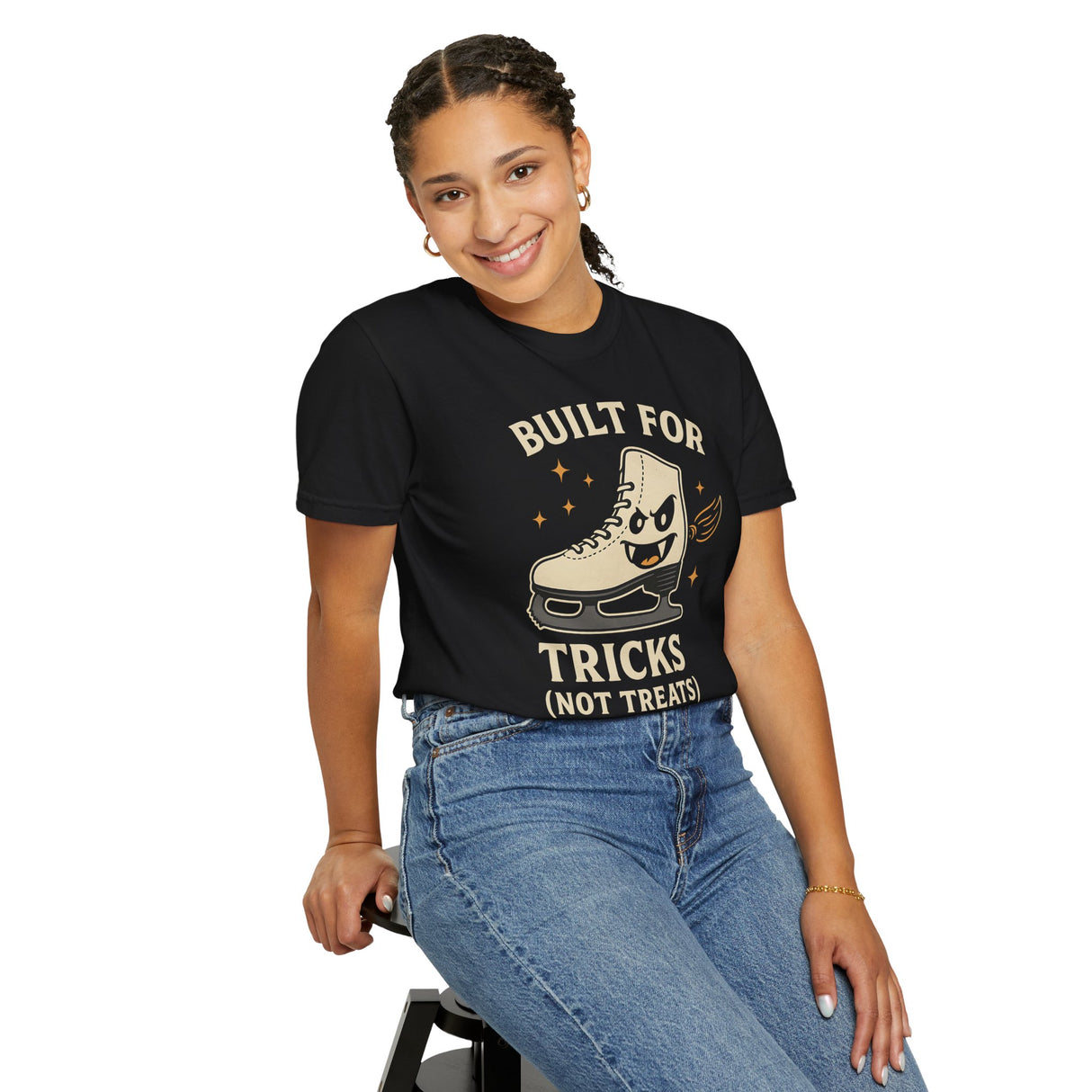 Person wearing a black t-shirt with a graphic and text, sitting on a stool against a white background