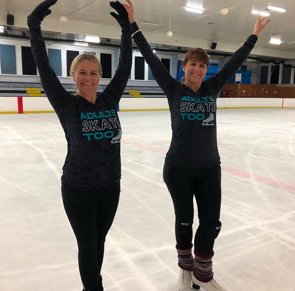 Two skaters in Adults Skate Too long-sleeve tops raising their arms on the ice