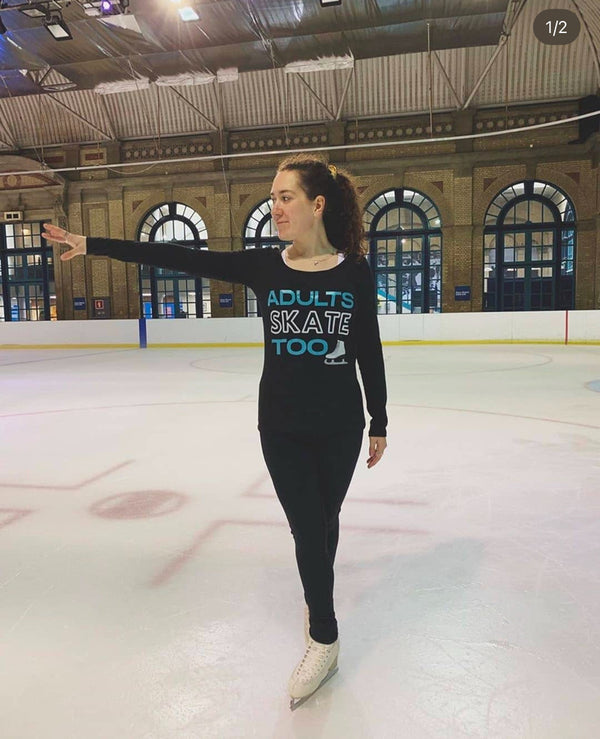 Skater in a black long-sleeve Adults Skate Too top with one arm out on a rink with arched windows
