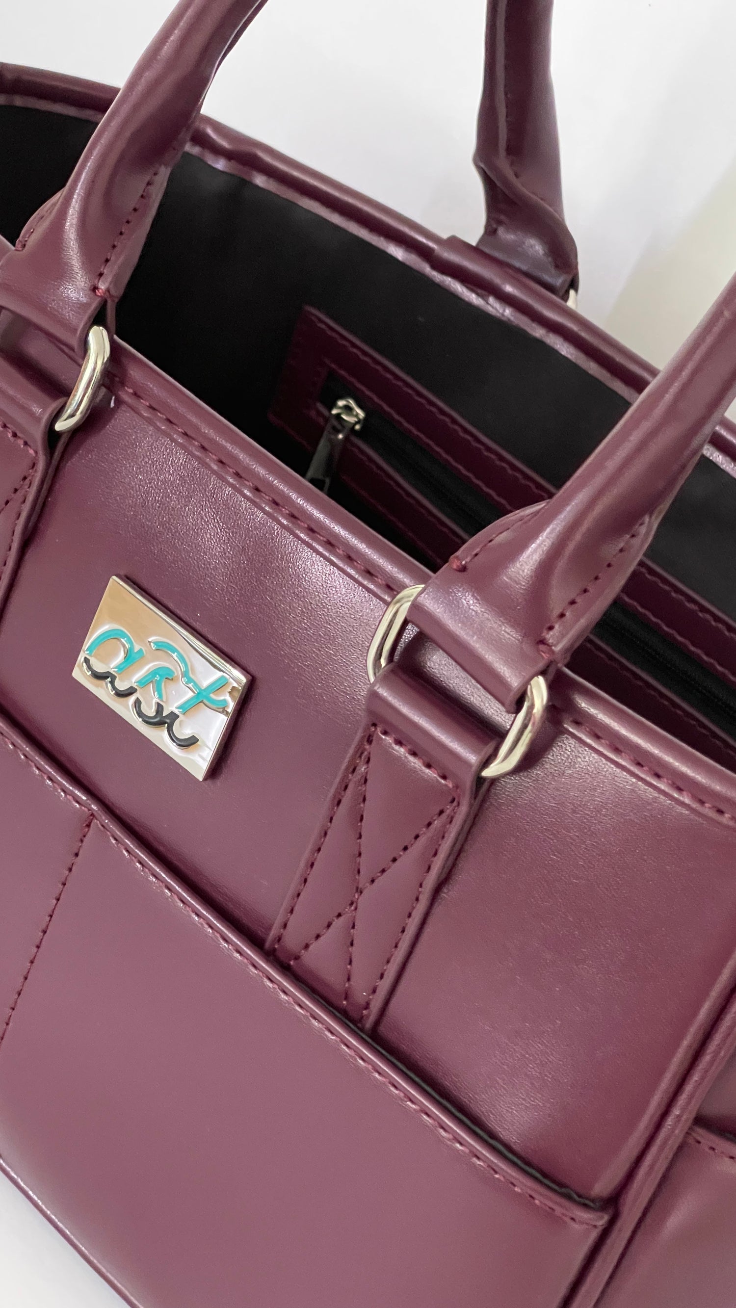 Close-up of a purple handbag with a visible brand logo on a white background
