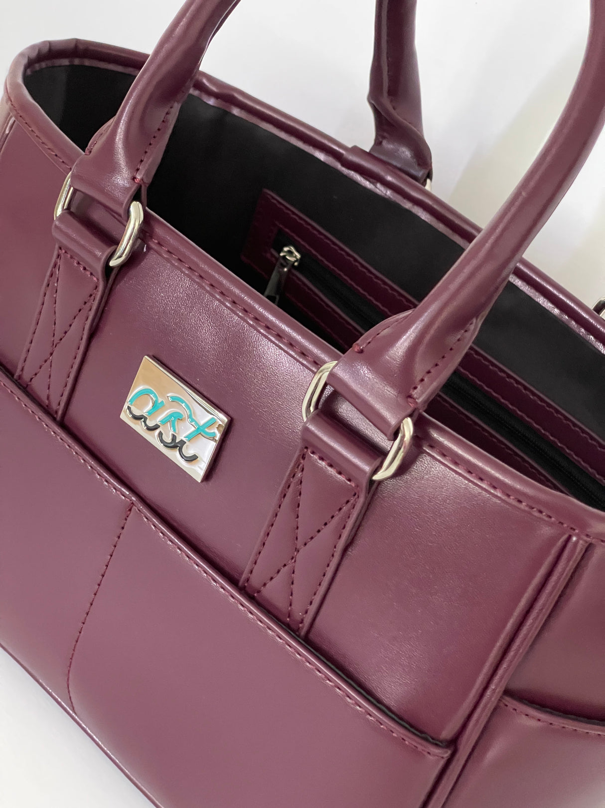 Close-up of a purple handbag with a visible brand logo on a white background