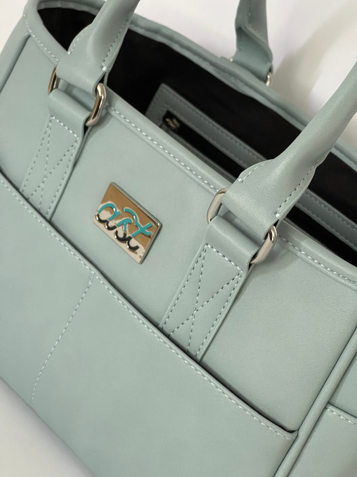 Light blue handbag with a visible brand logo on a white background