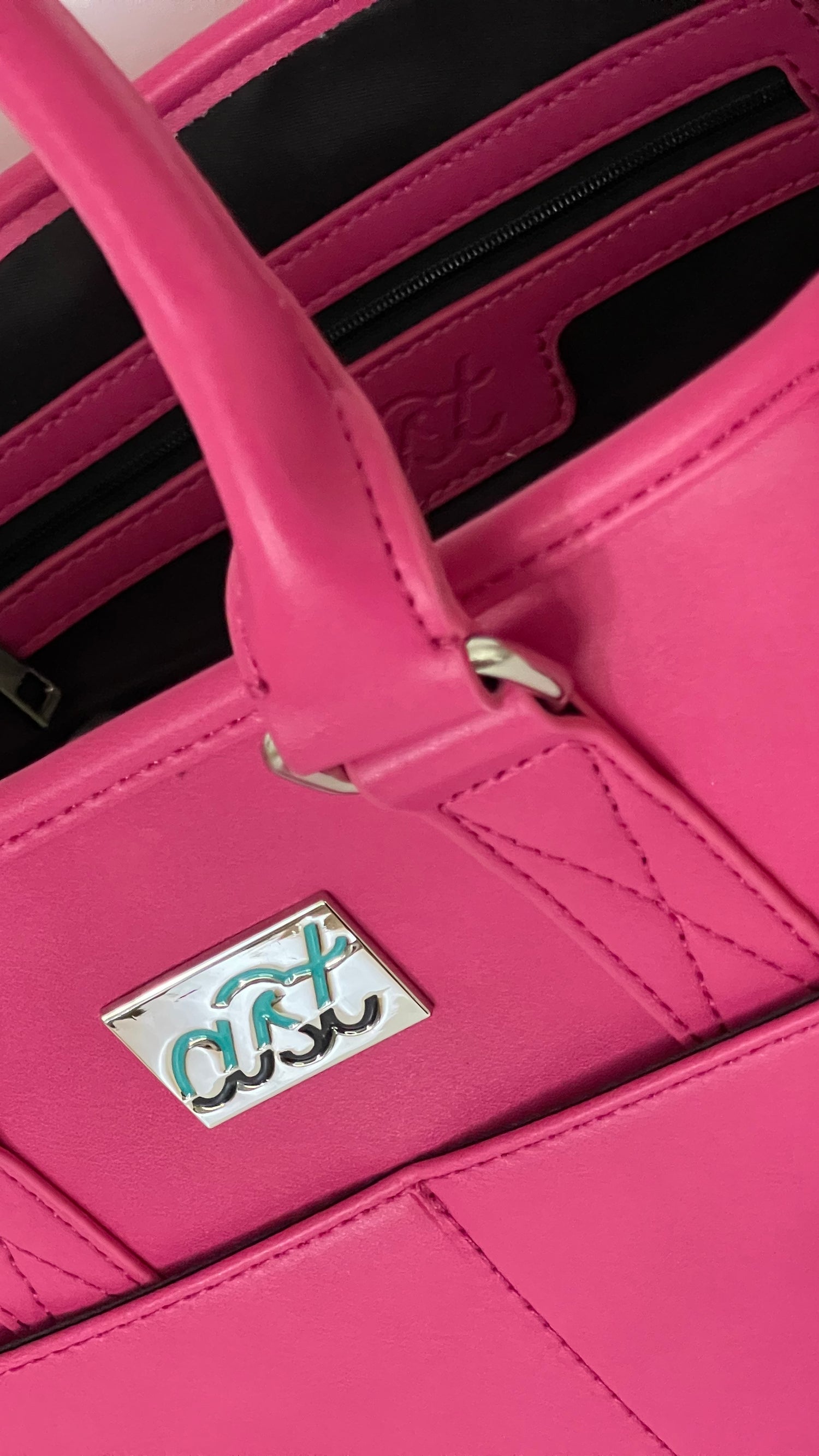 Close-up of a pink handbag with a visible brand logo on a white background
