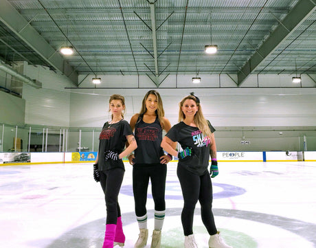 Three adult skaters in Adults Skate Too shirts standing on the ice at a rink