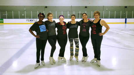 Six adult skaters in a row on the ice at the rink