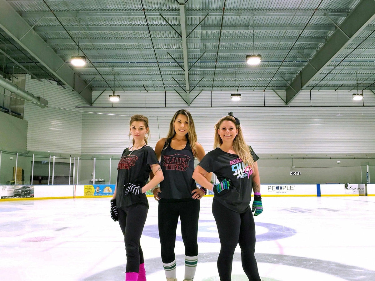 Three adult skaters in Adults Skate Too tees standing on the ice