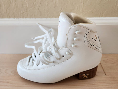 A new white figure skating boot without a blade, on a wooden floor