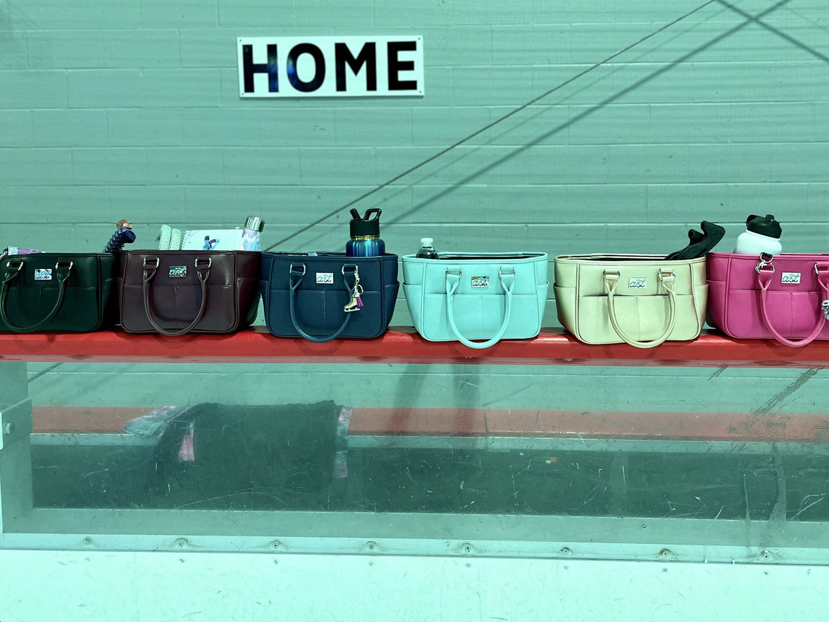 Six Rink Side Totes in different colors lined up on the rink boards under a HOME sign