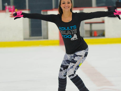 An adult skater balanced on one foot with her arms out on the ice