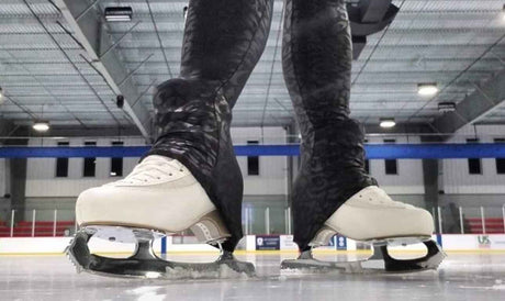 Two pairs of figure skates on the ice at a rink