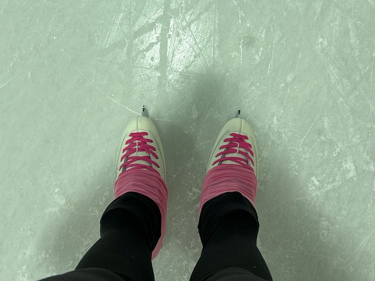 Figure skates with pink laces on the ice, seen from above