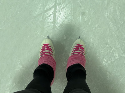 Figure skates with pink laces on the ice, seen from above