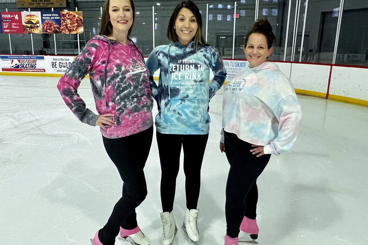 Three adult skaters in hoodies and leggings on the ice