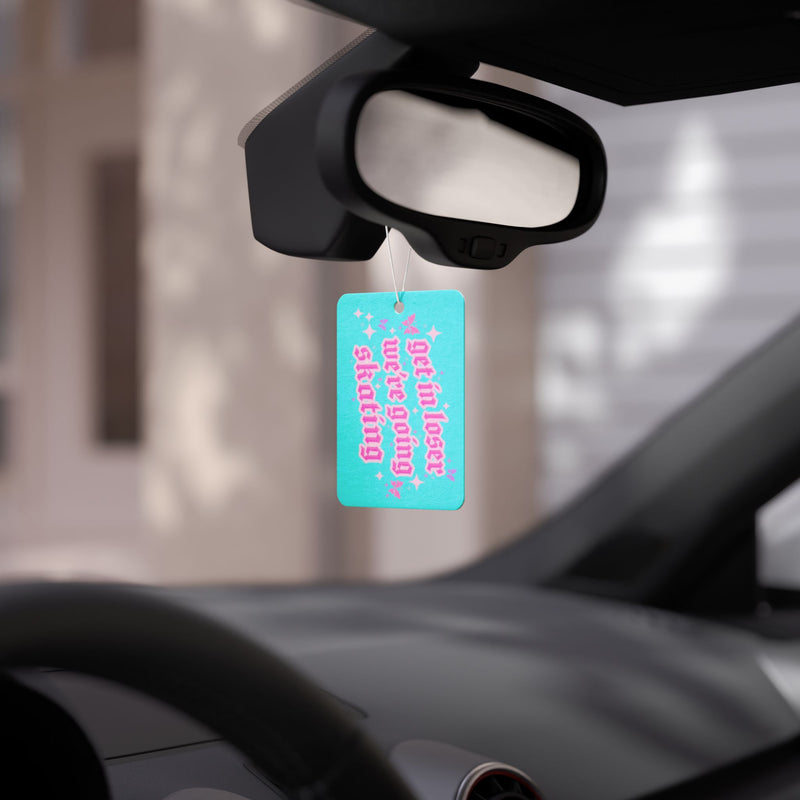 Car air freshener hanging from a car's rearview mirror with a blurred background