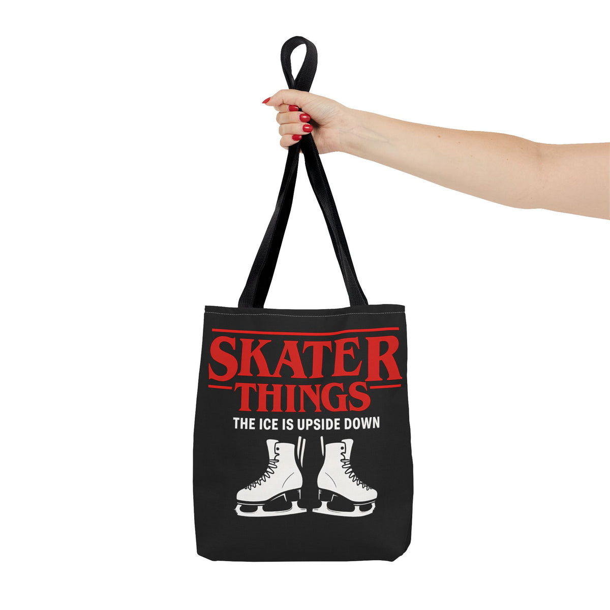 Black tote bag with red and white text and graphics, held by a hand on a white background