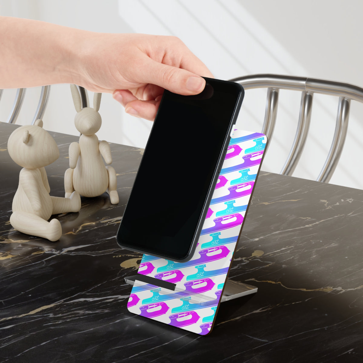 Phone being placed on a colorful phone stand on a marble surface.
