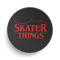Black circular object with red text 'SKATER THINGS' on a white background