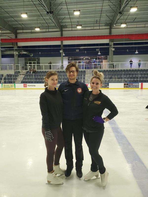 Three skaters standing together on an indoor rink