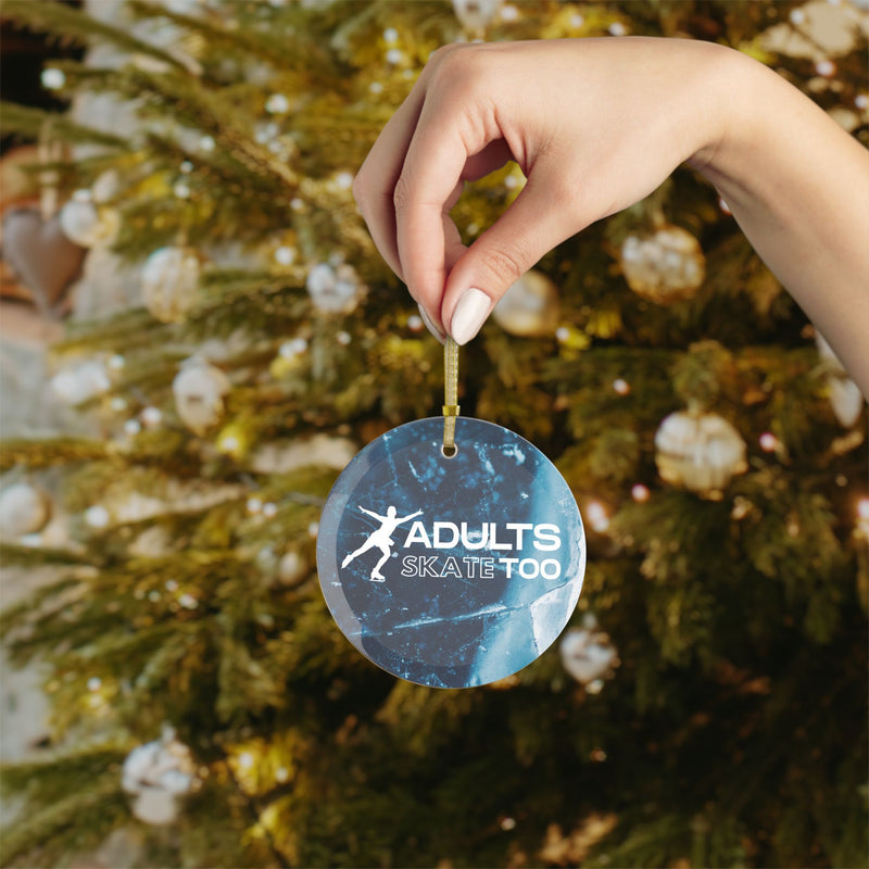 Hand holding a Christmas ornament with 'Adults Skate Too' text against a decorated tree background