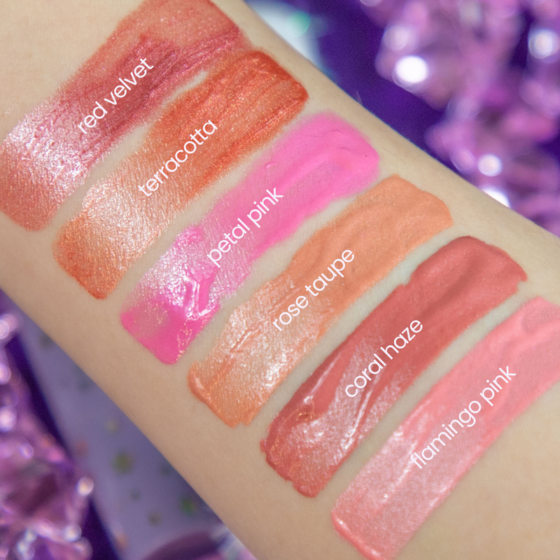 Lip gloss swatches on a hand with labeled colors against a purple glittery background