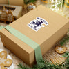 Wooden gift box with a green ribbon and a decorative label on a festive background with cookies and Christmas decorations.