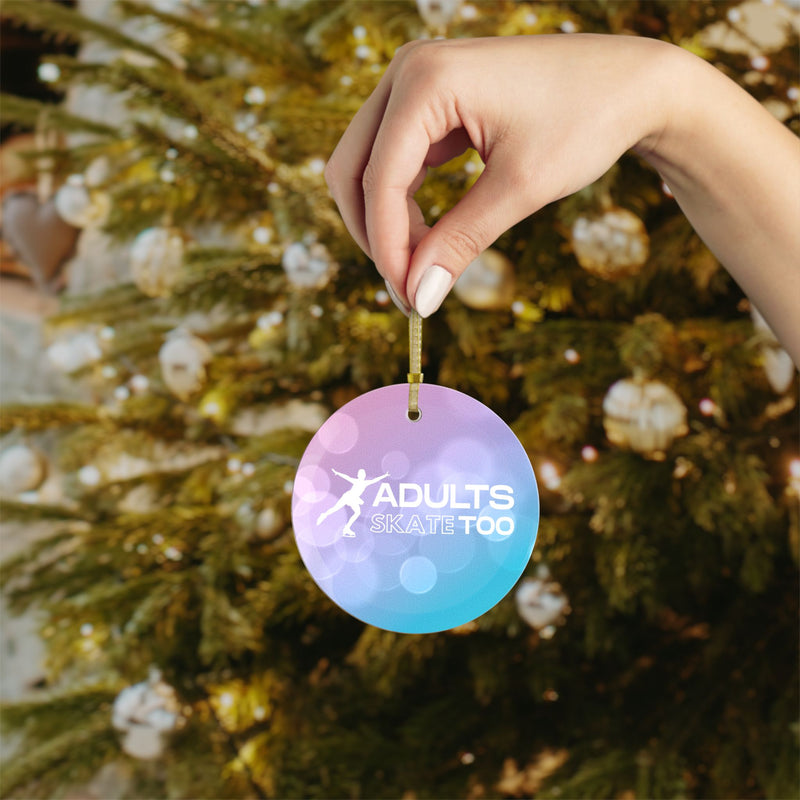 Hand holding a Christmas ornament with 'Adults Skate Too' text against a decorated tree background