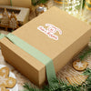 Wooden gift box with a green ribbon and 'Tickle or Twizzle' logo on a festive background with cookies and lights.
