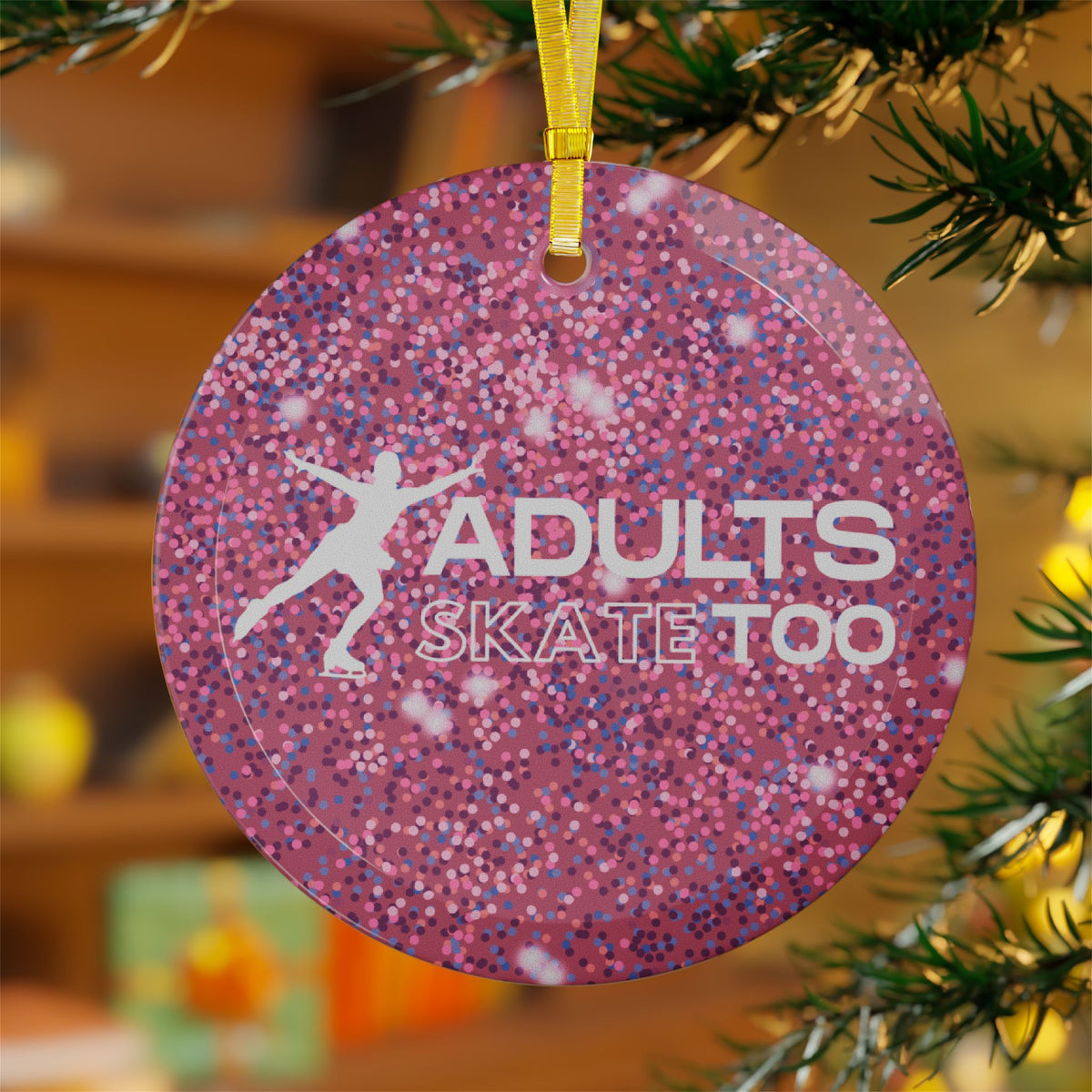 Pink glittery ornament with 'Adults Skate Too' text and silhouette of a skater, hanging on a Christmas tree.
