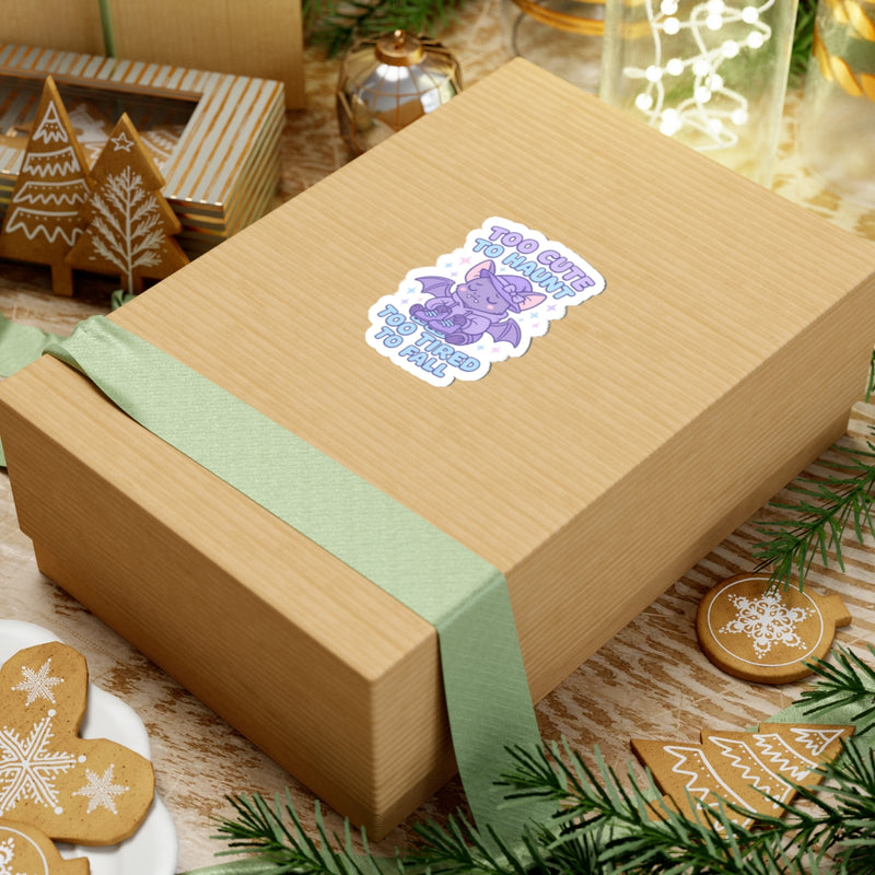 Gift box with a green ribbon and a decorative sticker on a festive background with cookies and lights.