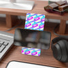 Colorful card with a geometric pattern on a desk with a phone, keyboard, and headphones.