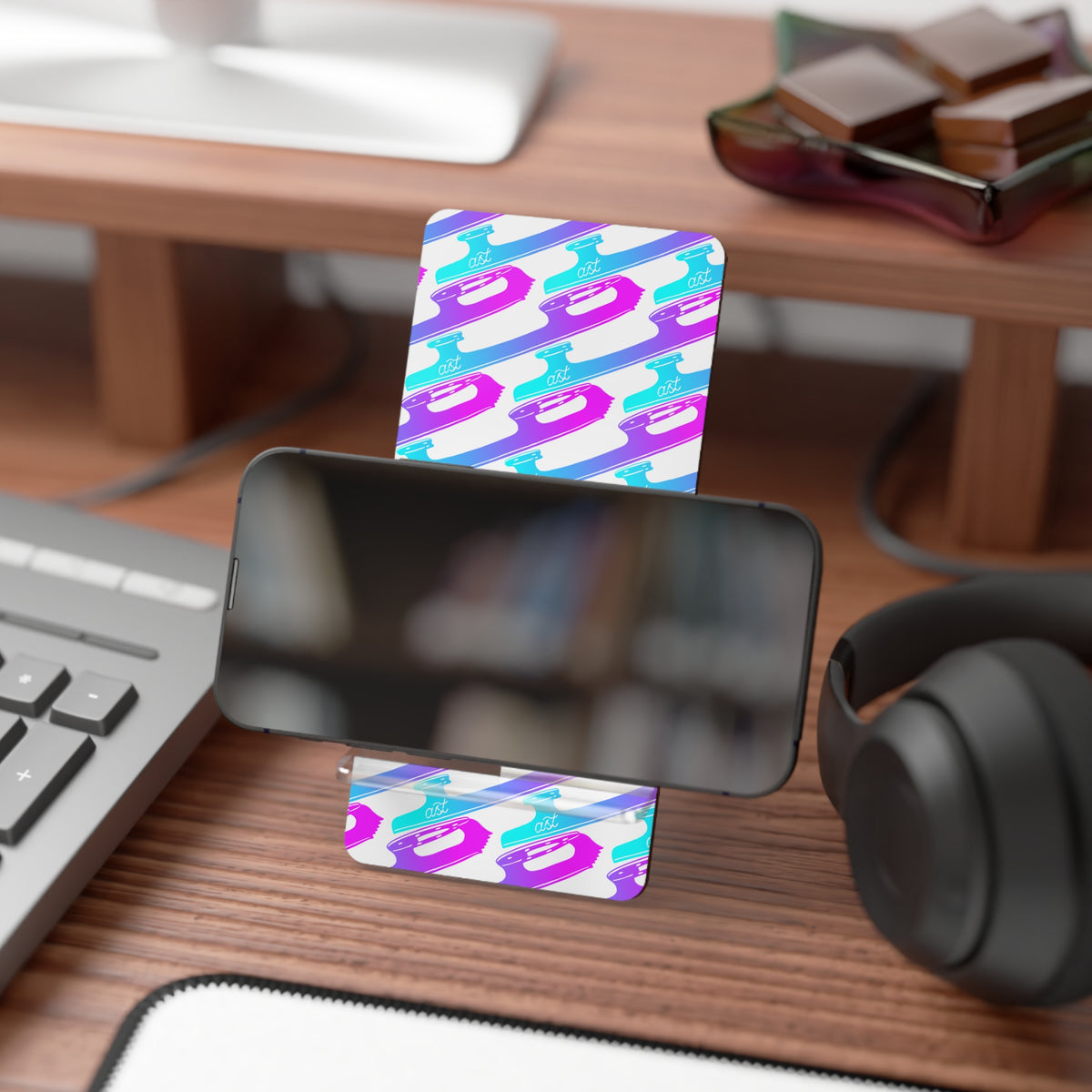 Colorful card with a geometric pattern on a desk with a phone, keyboard, and headphones.