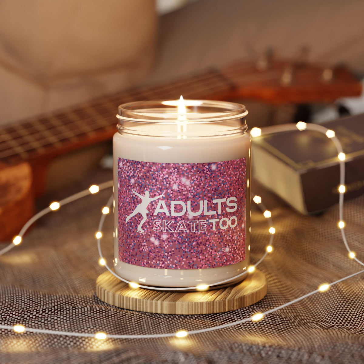 Candle in a jar with a pink label featuring the text 'Adults Skate Too' on a wooden surface with string lights.