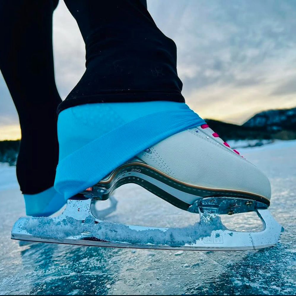Person wearing ice skates on a frozen lake with mountains in the background