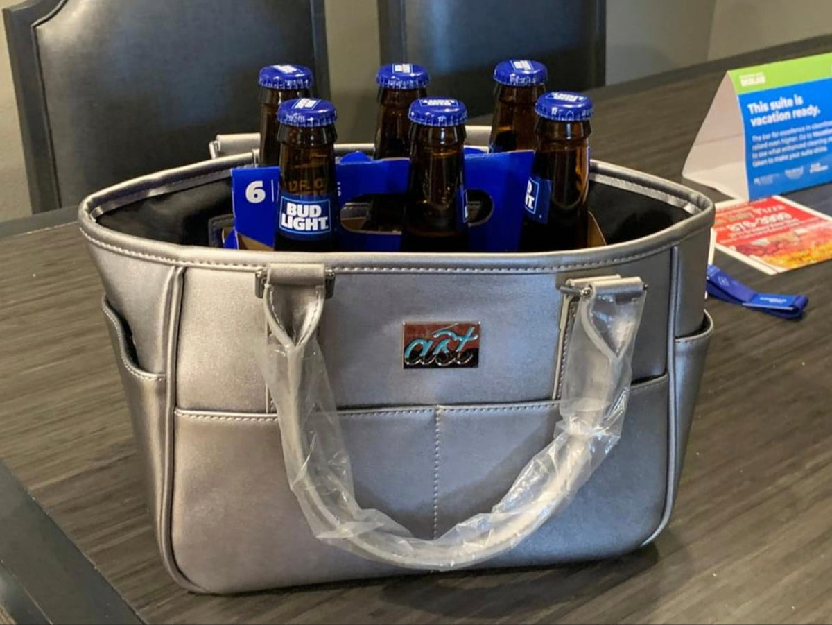 Silver cooler bag with six packs of beer on a table