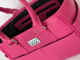 Close-up of a pink handbag with a visible brand logo on a white background