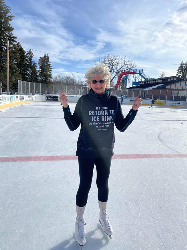 Skater giving two thumbs up in an If Found Return to Ice Rink sweatshirt on a sunny outdoor rink