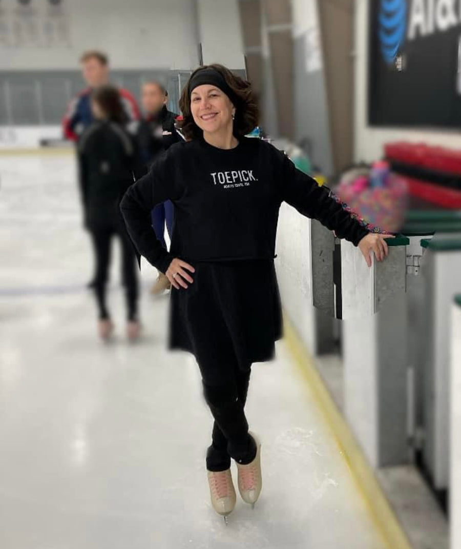 A skater on the ice in a black top with the Toepick design