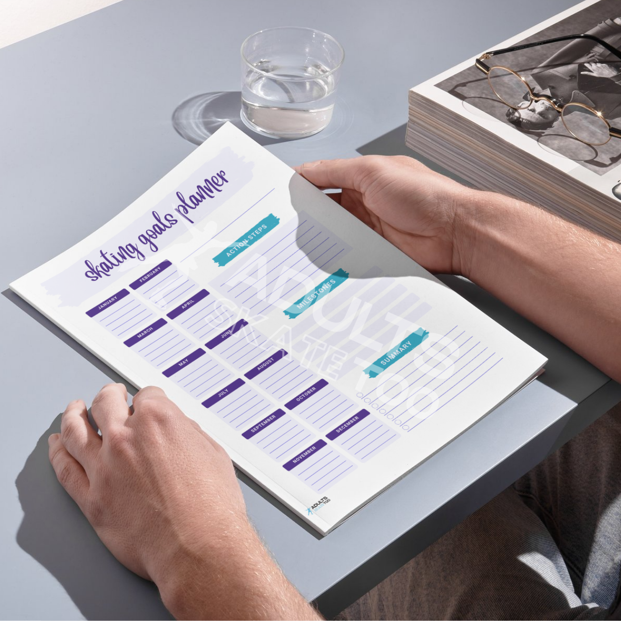 Person holding a planner with 'Skating Goals Planner' on a desk.