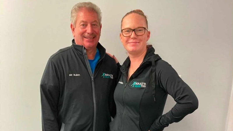 A coach and an adult skater standing together in Adults Skate Too jackets