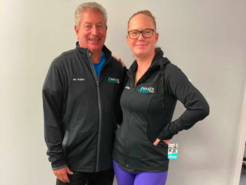 A coach and an adult skater standing together in Adults Skate Too jackets