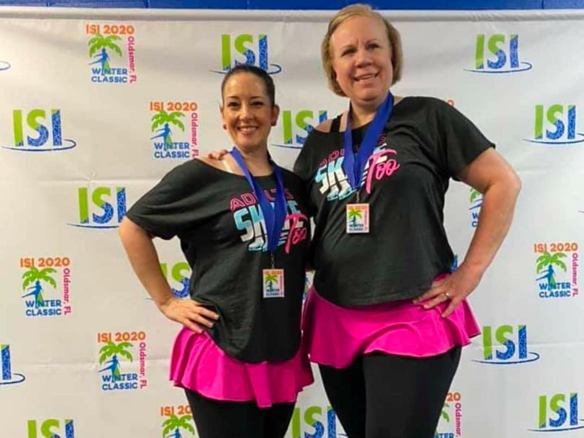 Two adult skaters with their medals in front of an ISI event backdrop