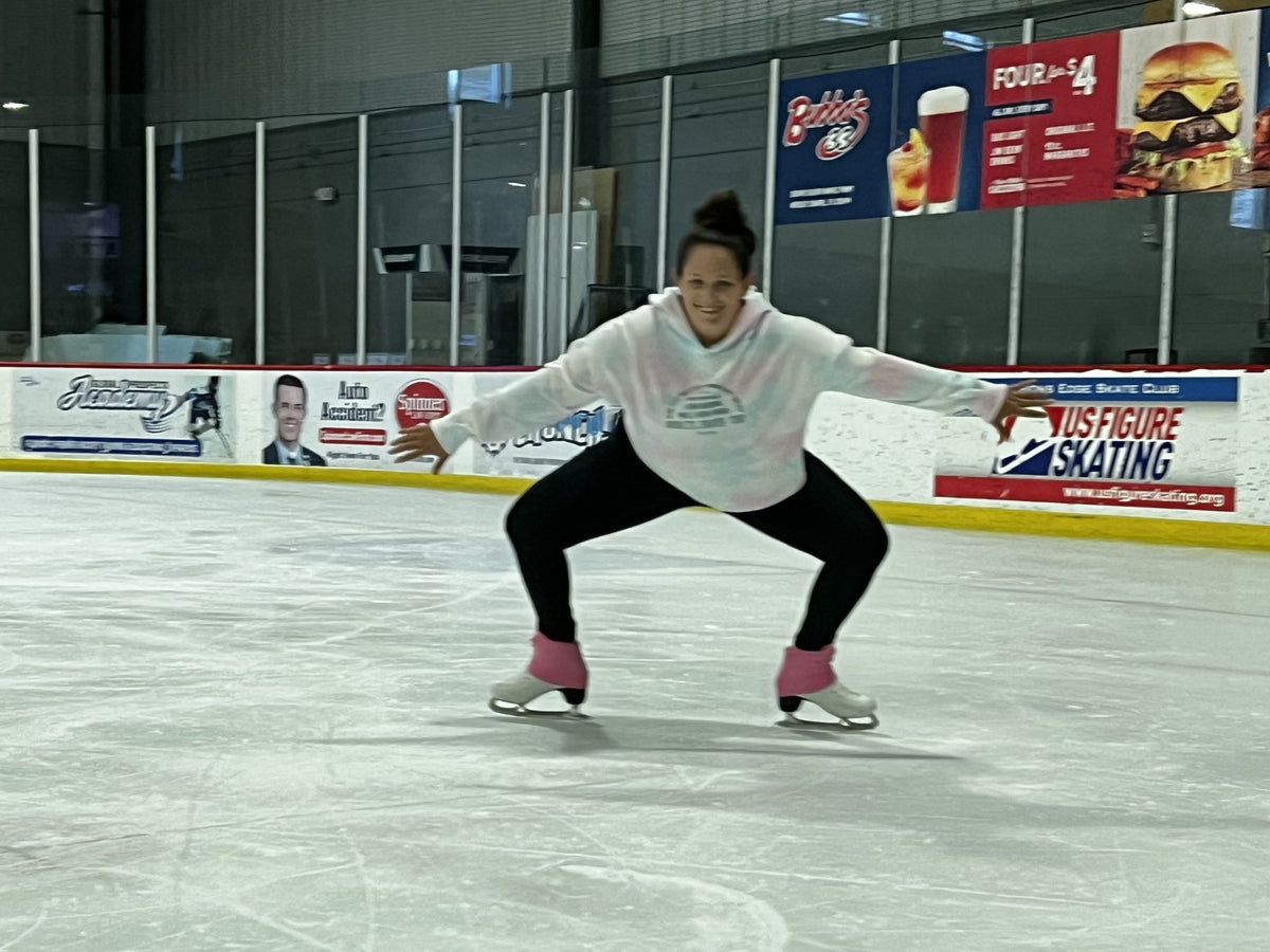A skater gliding low in a deep knee bend, arms out for balance