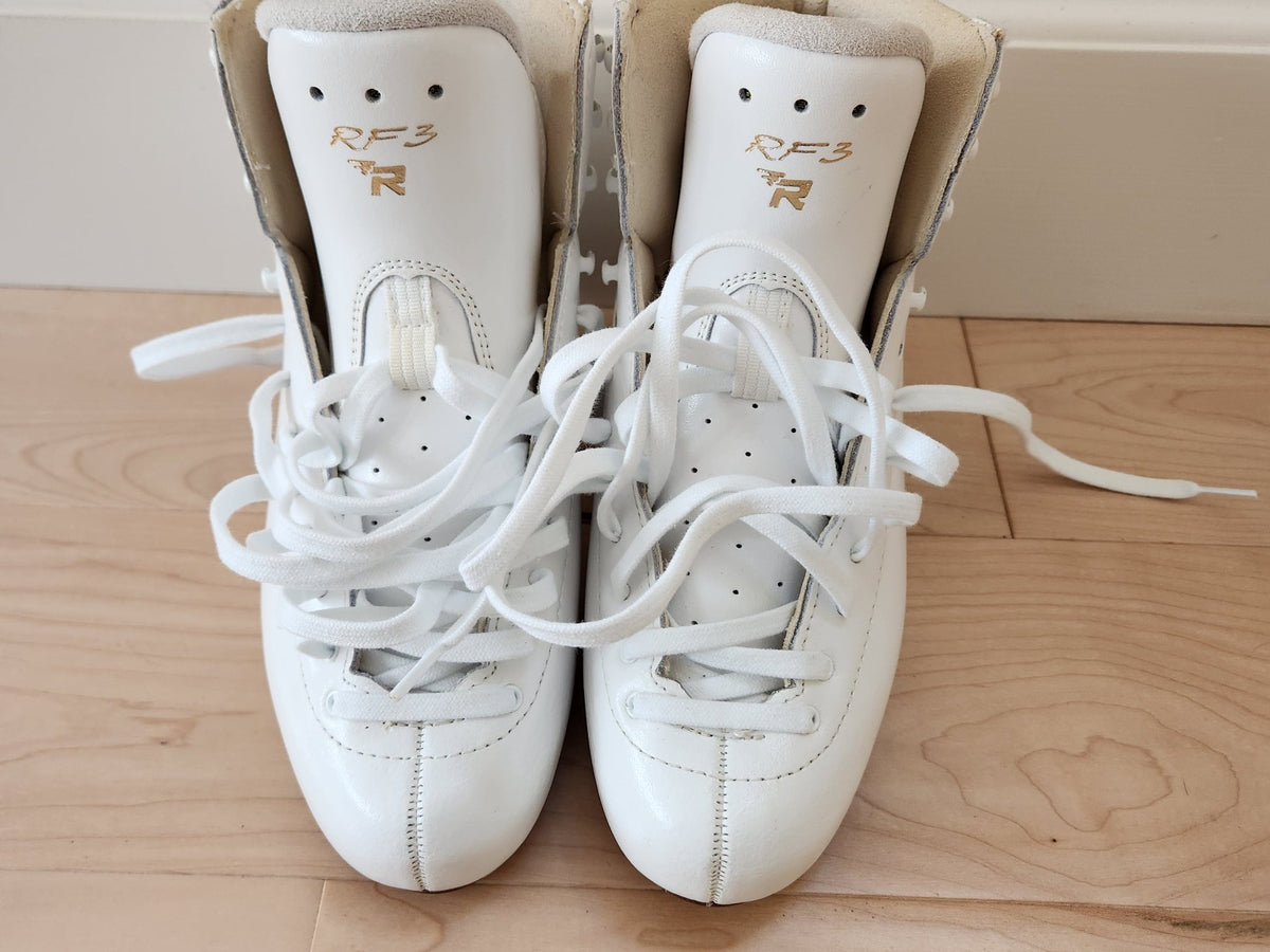 A new pair of white figure skating boots with the laces loose and the tongues up