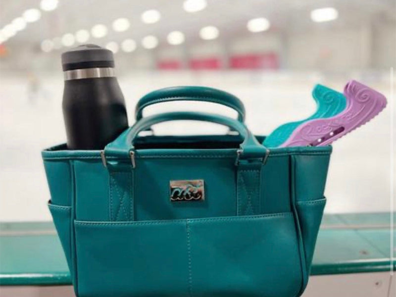 A teal Rink Side Tote on the rink boards with a water bottle and skate guards