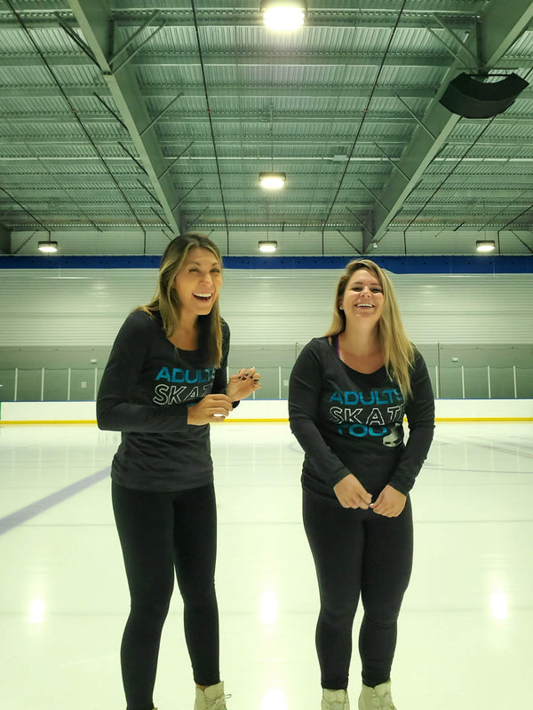 Two smiling skaters in Adults Skate Too long sleeves standing together on an indoor rink